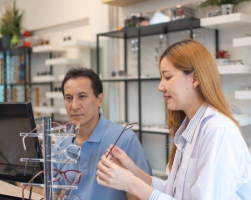 Attractive young female doctor and male customer selects eyeglass frames for made glasses ,eyeglasses store, optical shop. Startup new business, Small business or owner business.