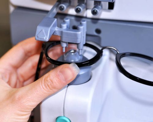 Female optician measuring and preparing glasses on the digital device in optical store
